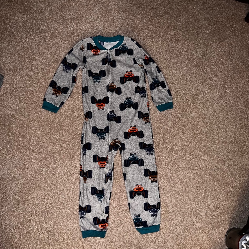 CARTER’S FLEECE SIZE 7/7A zip up one-piece pajama with monster truck theme.